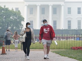 People walk near the White House in Washington, Thursday, June 8, 2023, as smoke from Canadian wildfires obscures the view. Air quality alerts in Washington, D.C., reached "code purple" status today, one notch below the "maroon" levels in neighbouring Baltimore.