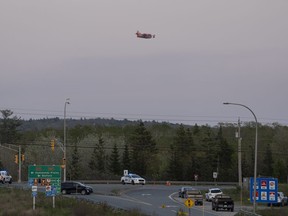 A water bomber plane flies over a RCMP roadblock as smoke fills the sky from an out-of-control fire in a suburban community outside of Halifax that quickly spread, engulfing multiple homes and forcing the evacuation of local residents on Sunday May 28, 2023.THE CANADIAN PRESS/Darren Calabrese