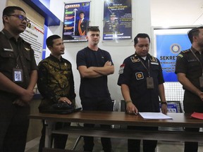 Bodhi Mani Risby-Jones from Queensland, Australia, center, accompanied by his lawyer Idris Marbawi, second left, stands with prosecutors and immigration officials during his transfer at the local immigration office in Meulaboh, Aceh, Indonesia on Wednesday, June 7, 2023. The Australian surfer who was jailed for attacking several people while drunk and naked in Indonesia's deeply conservative Muslim province of Aceh will be deported back to his country after he agreed to apologize and pay compensation, officials said Wednesday.