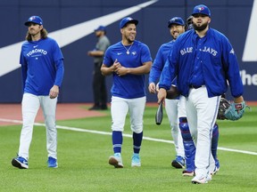 Toronto Blue Jays starting pitcher Alek Manoah, right, walks to the dugout with his fellow starting pitchers Kevin Gausman, left to right, Jose Berrios and Yusei Kikuchi prior to MLB baseball action against the Milwaukee Brewers in Toronto on Wednesday, May 31, 2023.THE CANADIAN PRESS/Frank Gunn