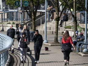 Pedestrians and runners at the seawall in Yaletown on a sunny day in Vancouver.