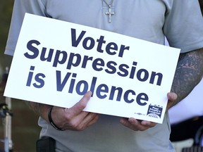 FILE - A person previously convicted of a felony felon holds a sign about voter suppression during a Poor People's Campaign assembly in Jackson, Miss., on Monday, April 19, 2021. The demonstrator was among speakers who called for Mississippi to simplify the way it restores voting rights to people convicted of some felonies. On Friday, June 30, 2023, the U.S. Supreme Court said it would not consider a case challenging Mississippi's practice of removing voting rights from people convicted of some crimes.