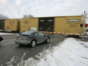 FILE - Cars wait for a train to pass, in Valley, Neb., Wednesday, Jan. 17, 2007. With the rail industry relying on longer and longer trains to cut costs, the Biden administration is handing out $570 million in grants to help eliminate railroad crossings in 32 states. The grants announced Monday, June 5, 2023 will help eliminate more than three dozen crossings that delay traffic and sometimes keep first responders from where help is desperately needed.