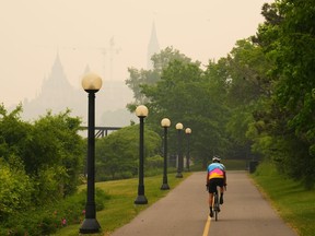 A cyclist rides as smoke from wildfires in Ontario and Quebec obscures Parliament Hill in Ottawa on Tuesday, June 6, 2023.