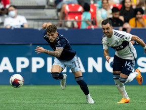 Sporting Kansas City's Marinos Tzionis (77) and Vancouver Whitecaps' Luís Martins (14) chase the ball during the first half of an MLS soccer match in Vancouver, on Saturday, June 3, 2023.