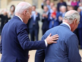 U.S. President Joe Biden places his hand on the back of Britain's King Charles III as they walk in the Quadrangle after ceremonial welcome at Windsor Castle on July 10, 2023.