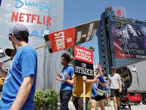 People carry signs as SAG-AFTRA members walk the picket line in solidarity with striking WGA (Writers Guild of America) workers outside Netflix offices on July 11, 2023 in Los Angeles.
