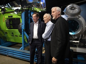 Canadian Geographic President and CEO John Geiger, left, scientific adviser Joe MacInnis and explorer and filmmaker James Cameron pose for a photo in front of the Deepsea Challenger and a capsule on display at the Royal Canadian Geographic Society, Tuesday, July 18, 2023 in Ottawa. Cameron says the implosion of the Titan submersible that killed five people in June was an extreme outlier.