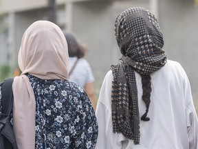 Women wear hijabs as they walk along a street in Montreal