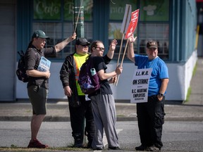 International Longshore and Warehouse Union workers wave at cars driving past while picketing outside of the BC Maritime Employers Association Dispatch Centre after a 72 hour strike notice and no agreement made on the bargaining table in Vancouver, on Saturday, July 1, 2023.