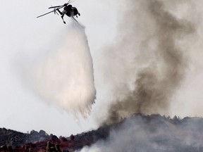 A helicopter makes a water drop on the Reche Fire west of Mountain Ranch Road as the fire grows to over 400 acres in the Reche Canyon near Moreno Valley, Calif., on Friday, July 14, 2023.