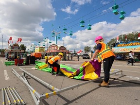 Workers on setup duty on the Calgary Stampede midway, Tuesday, July 4, 2023.
