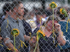 A woman weeps as mourners tie yellow ribbons and flowers to a fence following public vigil for Karolina Huebner-Makurat, in Toronto, Monday, July 17, 2023. The mother of two was killed by a stray bullet on July 7 after a shooting in her Leslieville neighbourhood.