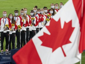 Members of the Canadian women's soccer team watch the flag raise after being presented with their gold medals at the Tokyo Olympics in Tokyo, Japan on Friday August 6, 2021. If an obsession with medals contributed to Canada's safe sport crisis, how will the country measure success in Paris?