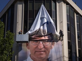 Workers remove an electoral poster showing Alberto Feijoo, leader of the mainstream conservative Popular Party, at the party headquarters in Madrid, Spain, Monday, July 24, 2023. Spaniards woke up Monday to find their country in political disarray after elections a day earlier left no party with a clear path to forming a government.