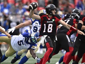 Winnipeg Blue Bombers defensive end Willie Jefferson (5) grabs onto the jersey of Ottawa Redblacks quarterback Dustin Crum (18) as he attempts to throw the ball, during first half CFL football action in Ottawa on Saturday, July 15, 2023.