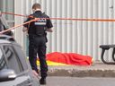A police officer stands next to the body of mobster Francesco Del Balso who was shot and killed outside a gym in Montreal on June 5, 2023.