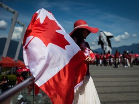 A woman waves a Canadian flag while sporting a patriotic outfit during Canada Day celebrations.