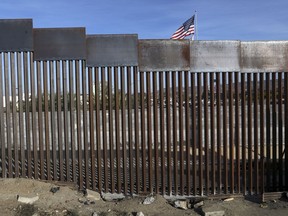 FILE - A United States flag flies behind the border fence that divides Mexico and the U.S., in Tijuana, Mexico, Nov. 21, 2018. Nearly a thousand migrants that recently crossed from Guatemala into Mexico formed a group Saturday, July 15, 2023, to head north together in hopes of reaching the border with the United States.