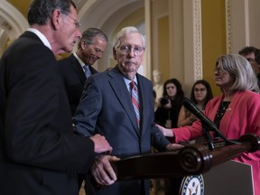 Senate Minority Leader Mitch McConnell, R-Ky., center, is helped by, from left, Sen. John Barrasso, R-Wyo., July 26.