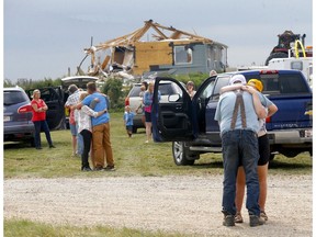 Residents comfort each other after a tornado destroyed their property on Highway 2A between Didsbury and Carstairs on Saturday, July 1, 2023.