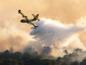 A firefighting plane sprays water to extinguish wildfire at Ciovo island, Croatia, Thursday, July 27, 2023. A large fire is reported on the island of Ciovo, close to Split on the Croatian Adriatic coast.