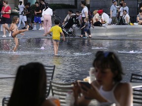 Children cool off in a public fountain in Milan, Italy, Saturday, July 15, 2023. Temperatures reached up to 42 degrees Celsius in some parts of the country, amid a heat wave that continues to grip southern Europe.