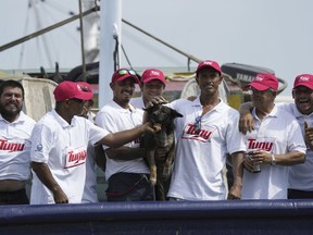 The crew of the Mexican tuna boat "Maria Delia" pose for photos with Bella, the dog of Australian Timothy Lyndsay Shaddock, both of whom they rescued from a incapacitated catamaran in the Pacific Ocean, as they bring the pair to port in Manzanillo, Mexico, Tuesday, July. 18, 2023. After being adrift with his dog for three months, Shaddock and his dog Bella were rescued some 1,200 miles from land.