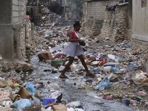 A girl walks through a ravine filled with garbage in Port-au-Prince, Haiti, Thursday, July 13, 2023.