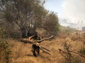 Volunteers cutting trees as a wildfire approaches the village of Vati, on the Aegean Sea island of Rhodes, southeastern Greece, on Tuesday, July 25, 2023. A third successive heat wave in Greece pushed temperatures back above 40 degrees Celsius (104 degrees Fahrenheit) across parts of the country Tuesday following more nighttime evacuations from fires that have raged out of control for days.