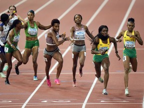 Canada's Aiyanna Stiverne passes the baton to teammate Kyra Constantine as members of Jamaica run next to them in a Women's 4 X 400-meters relay heat during the World Athletics Championships in Budapest, Hungary, Saturday, Aug. 26, 2023.&ampnbsp;Canada's women's 4x400-metre relay team finished fourth at the World Athletics Championships on Sunday.