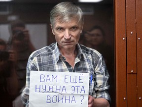 Jailed Russian dissident Alexei Gorinov, a Moscow city councillor, stands with a poster reading "Do you still need this war?"