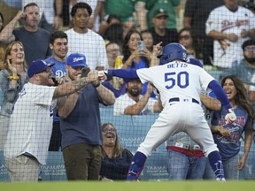 Los Angeles Dodgers' Mookie Betts fist bumps a fan after hitting a home run.