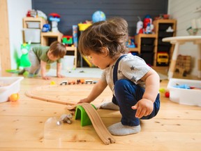 Little boys play with a wooden railroad in a stylish nursery. Home comfort.