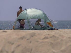 A family sets their beach tent next to a sand berm as winds move in Seal Beach, Calif., Friday, Aug. 18, 2023. Hurricane Hilary is churning off Mexico's Pacific coast as a powerful Category 4 storm threatening to unleash torrential rains on the mudslide-prone border city of Tijuana before heading into Southern California as the first tropical storm there in 84 years.