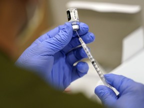 . A health-care worker fills a syringe with a COVID-19 vaccine