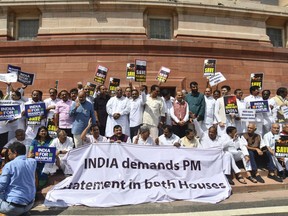 FILE - Opposition lawmakers demanding a statement from Prime Minister Narendra Modi on the violence in Manipur state carry placards and a banner with name of "INDIA" outside the Parliament building in New Delhi, India, July 24, 2023. India's opposition accused Modi of choosing silence while the northeastern state governed by his party convulsed in ethnic violence as Parliament began debate Tuesday on a no-confidence motion certain to be defeated. (AP Photo, File)