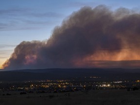 FILE - Smoke from the Calf Canyon/Hermits Peak Fire drifts over Las Vegas, N.M., on May 7, 2022. Federal emergency managers said Friday, Aug. 4, 2023, that they're making more progress in compensating victims of the Hermits Peak/Calf Canyon wildfires sparked last year by the U.S. Forest Service.