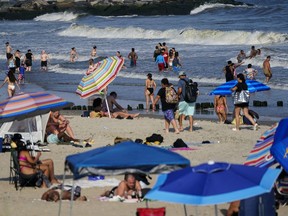 FILE - People enjoy the water at Rockaway Beach, Tuesday, July 19, 2022, in the Queens borough of New York. Authorities say a woman was critically injured when a shark bit her on the leg Monday, Aug. 7, 2023, while she was swimming at Rockaway beach.