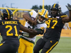 Edmonton Elks quarterback Tre Ford (2) makes some yards on the ground before being tackled by Hamilton Tiger Cats linebacker Simoni Lawrence (21) during first quarter football action in Hamilton, Ont., on August 17, 2023.