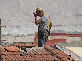 A worker pauses in the heat on a roof of a building in Madrid, Spain, Tuesday, Aug. 8, 2023. Spain is set to experience several days of extreme heat with temperatures in many parts set to rise above 40 degrees Celsius (104 degrees Fahrenheit).