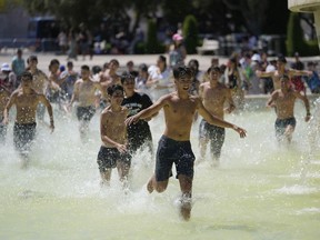 A group of pilgrims cool off playing in a fountain in front of the Jeronimos Monastery where Pope Francis will visit in Lisbon, Wednesday, Aug. 2, 2023. Pope Francis has started his five-day pastoral visit to Portugal Wednesday that includes his participation at the 37th World Youth Day, and a pilgrimage to the holy shrine of Fatima.