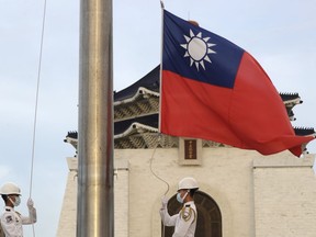 FILE - Two soldiers lower the national flag during the daily flag ceremony on Liberty Square of the Chiang Kai-shek Memorial Hall in Taipei, Taiwan, July 30, 2022. China sent navy ships and a large group of fighter jets toward Taiwan, continuing its military pressure on the island, Taiwan's defense ministry said Thursday, Aug. 10, 2023.
