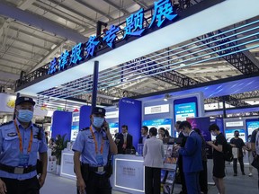 Police officers patrol past visitors seeking information at a special exhibition of legal services during the China International Fair for Trade in Services (CIFTIS) at the Shougang venue in Beijing on Sept. 1, 2022. One of the world's biggest law firms said Thursday, Aug. 10, 2023 it is separating from the Chinese firm that was part of its global network for eight years, citing changes in cybersecurity and other rules that have rattled foreign companies.