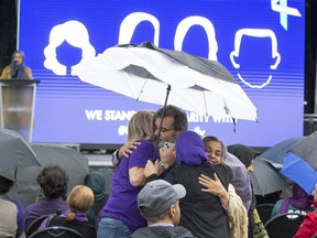 Crowd members embrace during a first-anniversary gathering in London at a memorial to four members of a Muslim family from the city who were struck and killed by a vehicle at an intersection in their neighbourhood while out walking on June 6, 2021. (Derek Ruttan/The London Free Press)