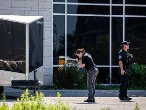 An Ottawa police officer snaps photos of bullet casings that lay in the back parking lot area of the Infinity Convention Centre on Sunday.
