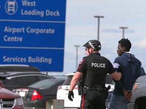 Calgary police take a man into custody after a shooting at the Calgary International Airport on Wednesday.
