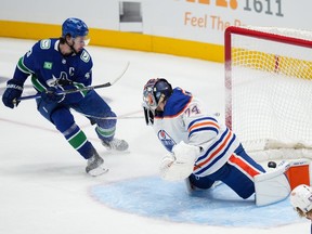 Vancouver Canucks' Quinn Hughes, back left, scores his first goal against Edmonton Oilers goalie Stuart Skinner during the second period of a pre-season NHL hockey game in Vancouver, B.C., Saturday, Sept. 30, 2023.