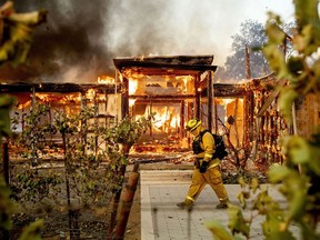 FILE - Woodbridge firefighter Joe Zurilgen passes a burning home as the Kincade Fire rages in Healdsburg, Calif., on Oct. 27, 2019. California Insurance Commissioner Ricardo Lara announced plans on Thursday, Sept. 21, 2023, aimed at keeping home insurers in California amid increasing risks from climate change.
