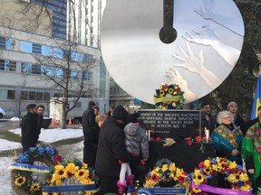 The Holodomor memorial in Edmonton, surrounded by people and flowers